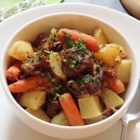 bowl of irish stew on plate with spoon