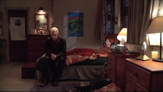 Spike is sitting on the end of Willow's bed, looking ashamed, while Willow sits against the pillows looking sympathetic.