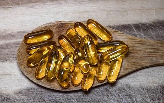 Fish oil capsules in a wooden spoon.