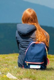 Girl with backpack sitting in gras