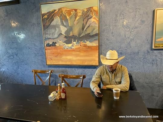 cowboy checks his phone at V6 Coffee Bar at Gage Hotel in Marathon, Texas