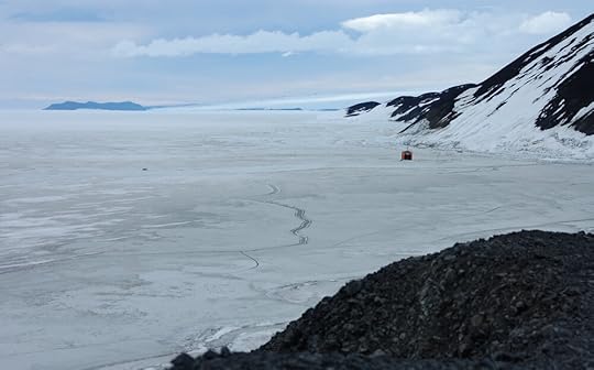 The view to Cape Evans from the end of Hut Point. Cape Evans is the smudge at horizon level, leftmost of the three long low shapes at upper centre. The sea ice here is walkable, despite the cracks; in May of 1916 it was not.