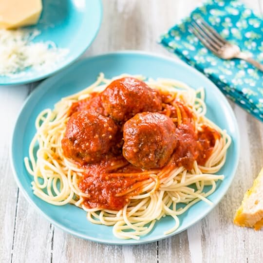 A light blue plate with a serving of cooked spaghetti noodles with 3 meatballs with spaghetti sauce on top of the pasta