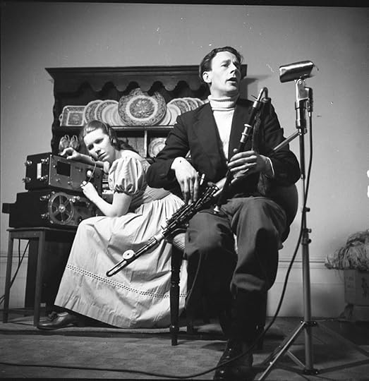 In the foreground, S��amus Ennis sits with his pipes. In the background, Jean Ritchie is leaning intently over her recording equipment.
