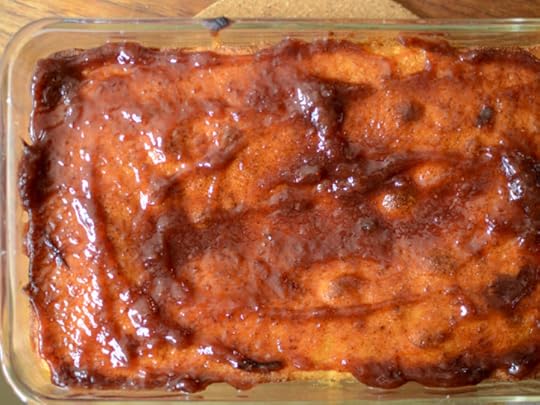 Finished cake in a glass baking pan with strawberry jam spread on top