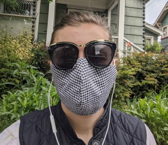 The author standing outside wearing a cloth face covering and dark sunglasses.
