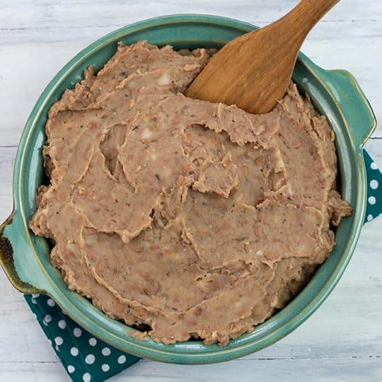 overhead photo looking down into a teal terra cotta serving bowl filled with the cooked Instant Pot Refried Beans