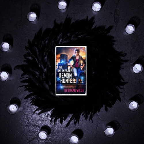 Cover of The Unlikeable Demon Hunter on black feathers surrounded by candles