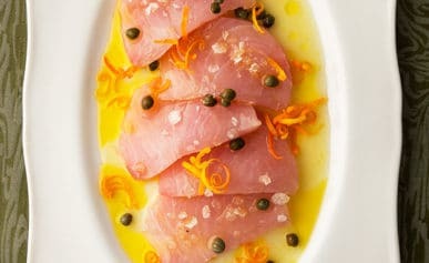 Slices of tuna crudo on a platter