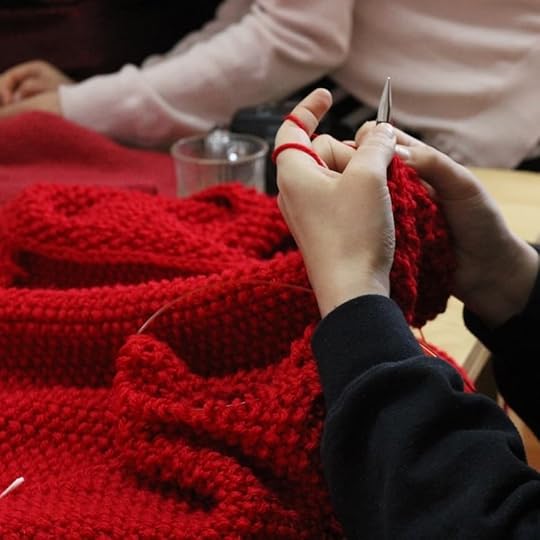 En la foto persona teje a palilo con lana roja