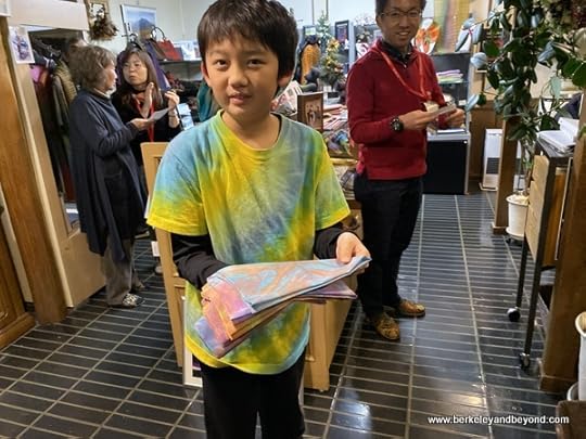 young boy delivers finished student projects at AlpenRose cafe at Geocolor: Hachimantai Geothermal Dyeing in Hachimantai city, Japan