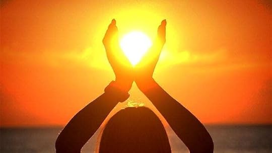 silhouette of woman with hands enclosing the setting sun