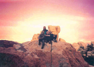 Group of people on top of a rock in front of a sunset