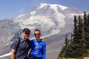 Two people in front of a large snow-covered mountain