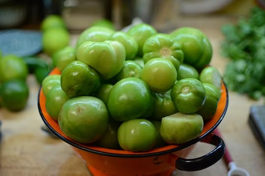 An orange colander filled with four pounds of husked and washed tomatillos.