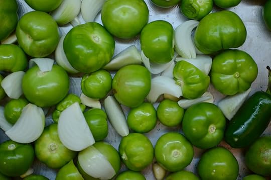 A baking sheet covered in tomatillos, quartered white onions and jalapenos.