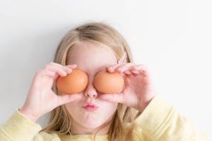girl holding eggs to eyes