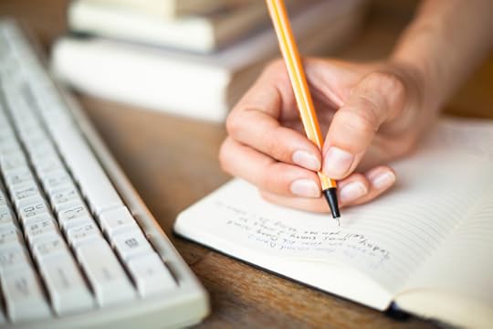 hand writing notes in notebook next to books