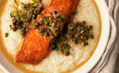 Salmon piccata served over a bowl of grits.
