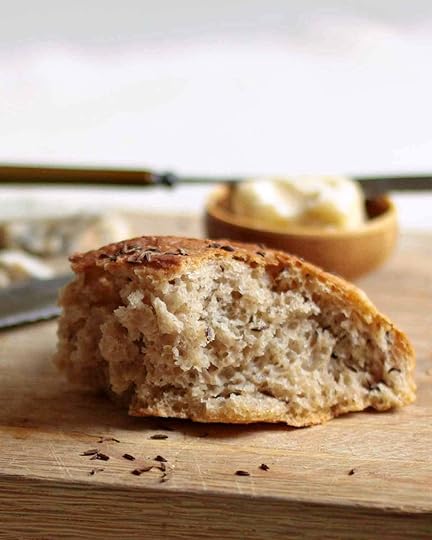 A piece of bread on a wooden cutting board for the writing 