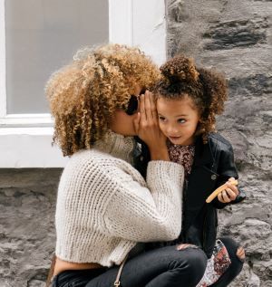Mother whispering into child's ear
