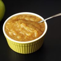apple next to green bowl of applesauce with spoon