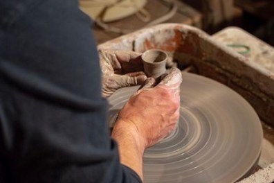 Potter making a raku vase on the pottery wheel.