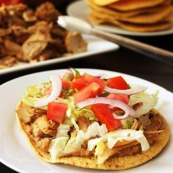 carnitas tostada on plate with other ingredients on table