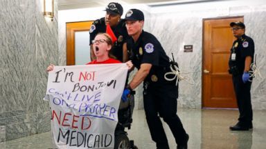 Photo of a disabled protester being forcibly removed by a law enforcement officer.