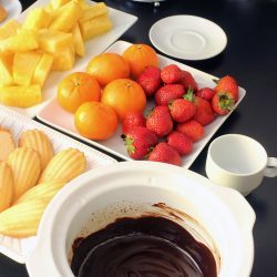 slow cooker crock full of chocolate fondue with plates of fruit and cake