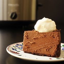 slice of cheesecake on plate near slow cooker