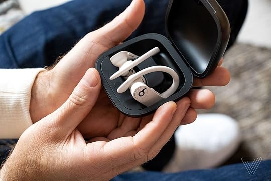 Powerbeats Pro earbuds pictured inside their case in someone's hand.