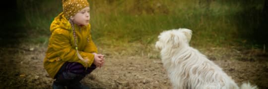 Little girl wearing yellow calling a white dog