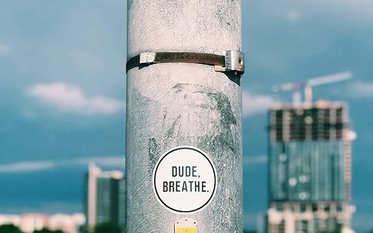 A sticker on a pole (overlooking a cityscape) reads 