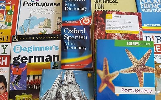 A stack of language learning books spread out on a table. Learning how to speak fluently can be overwhelming if you use too many materials.