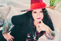 Michele on her sofa in a red hat