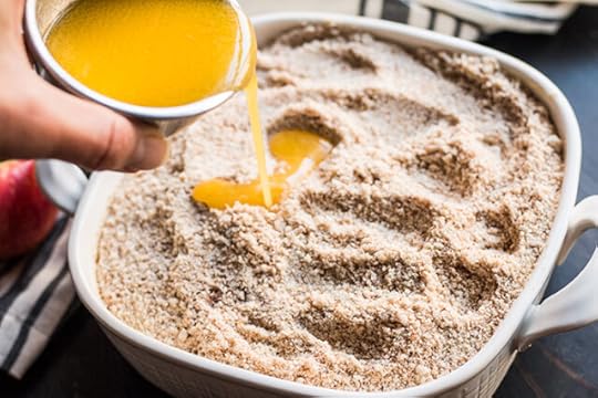 pouring melted butter over ingredients for a paleo apple dump cake recipe