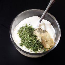 sour cream in glass bowl with dill dip ingredients on top