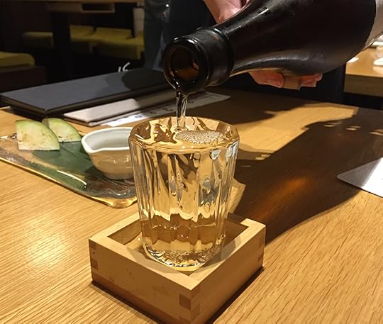 Sake cup overflowing into wooden box