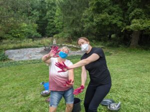 Two people in a yard with red-purple hands.