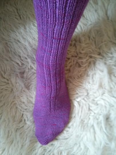 A photo of a hand-knit sock with a bright color.