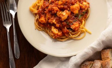 lobster fra diavolo with pasta and bread on a plate.