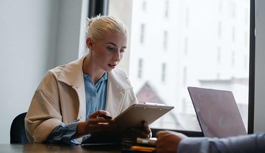 White woman looking at clipboard in office