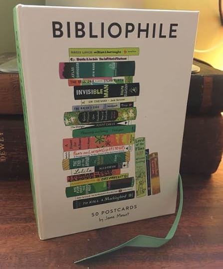 the cover of a box of postcards that is called BIBLIOPHILE and the postcard on the cover is a stack of books