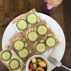 plate of crackers with toppings and cucumber slices