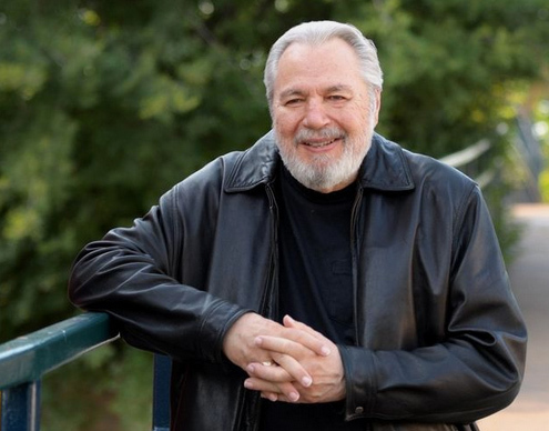 outdoor portrait of author John Lutz wearing a black shirt and jacket.