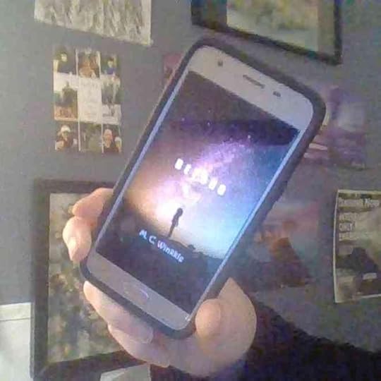 Beyond by M.C. Winkkle on a cell phone.On the cover: A girl in silhouette stands atop hills in front of a colorful starry sky.