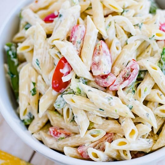 overhead photo of a white glass serving bowl filled with a pasta salad made with tomatoes and fresh asparagus