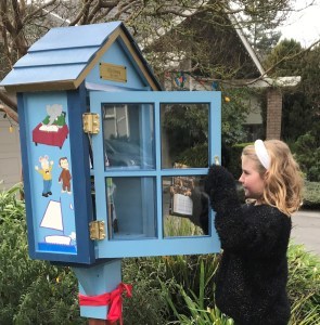 Little girls deposits a book in the Little Library