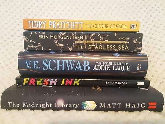 Stack of books including The Colour of Magic, Teh Starless Sea, The Invisible Life of Adie LaRue, Fresh Ink and The Midnight Library